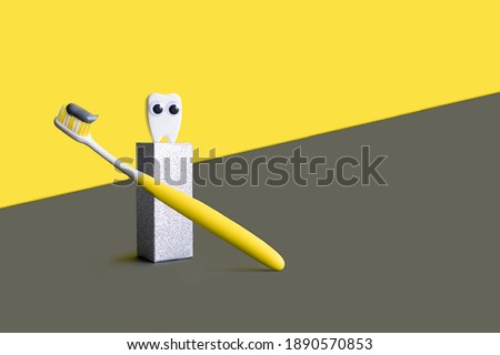 toothbrush with grey toothpaste and white toy tooth on podium in trending colors 2021 on Illuminating yellow, ultimate gray background. concept for dentistry. copy space, place for text.