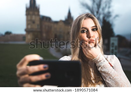 Young woman recording herself with a cell phone at the street.