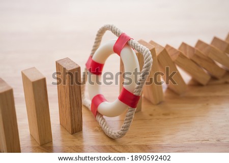 Lifebuoy stop wood block fall domino effect on office wooden table background. Life, health and property insurance business concept. Insurance is risk control management. Royalty-Free Stock Photo #1890592402