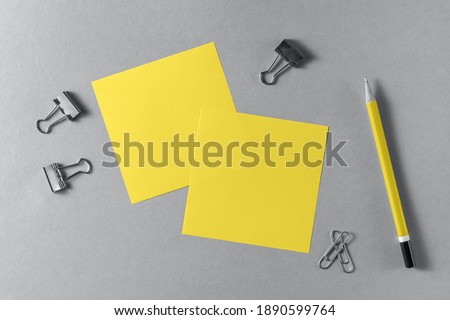 Yellow blank sheets of note paper and a wooden pencil on a grey background. Illumination and ultimate gray trendy colors 2021 year