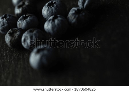 Detailed close up of group of blueberries in upper left corner on slate plate