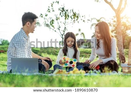 Happy asian family in the garden They play ukulele, singing, take pictures, eat together and have fun.