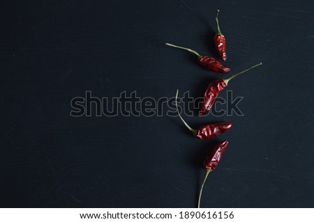 bunch of dry red hot chili peppers aligned on the right with space for your text on black background.