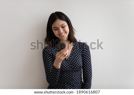 Addicted to technology millennial asian korean woman using mobile phone applications, enjoying communicating distantly online in social network or shopping isolated on grey white studio background.