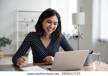 Happy young vietnamese korean woman in headset with microphone involved in educational video call conference conversation, studying remotely, consulting with teacher using computer application. Royalty-Free Stock Photo #1890617191