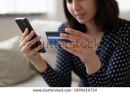 Close up young female mixed race korean client using e-banking application, entering information from plastic card, happy vietnamese money transferring money or making purchases in online store. Royalty-Free Stock Photo #1890618724