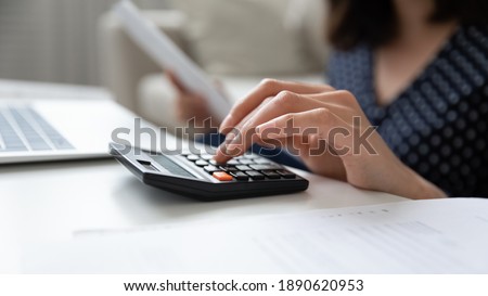 Close up millennial korean vietnamese woman using calculator managing domestic payments, summarizing monthly savings and expenditures, paying utility bills taxes, doing accounting financial paperwork. Royalty-Free Stock Photo #1890620953