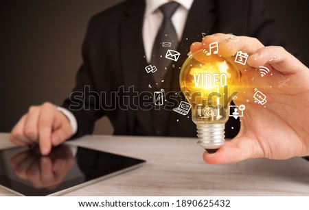 Businessman holding light bulb with VIDEO inscription, social media concept