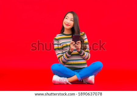 Portrait beautiful young asian woman use smart mobile phone on red isolated background
