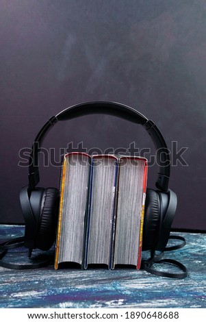 black headphones with a stack of books. The concept of audio books and modern education