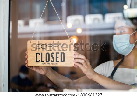Young asian owner retail,coffee shop woman turning sign board to closed with wearing face mask,protection to pandemic of coronavirus.Close store,restaurant or pub due to lockdown, quarantine of covid.