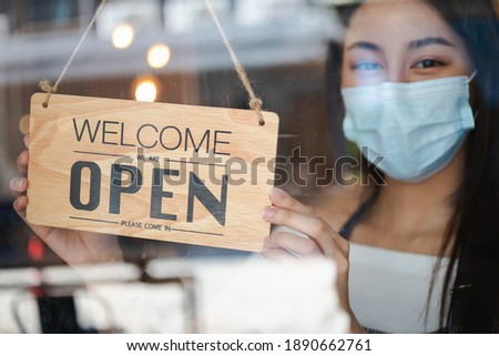 Owner retail,coffee shop woman turning sign board to open with wearing face mask ,protection to pandemic of coronavirus reopen store,restaurant after close lockdown quarantine in covid to new normal.