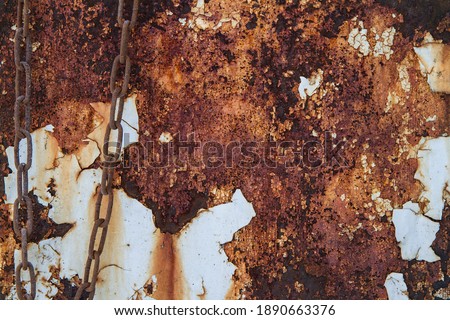 Rusty metal texture with paint. On the left side of the photo there is a double metal chain.