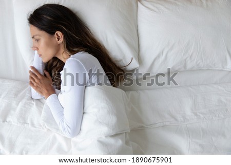 Top view unhappy depressed woman lying in empty bed alone, feeling lonely after quarrel with boyfriend, break up or divorce, upset young female thinking about problems, suffering from insomnia Royalty-Free Stock Photo #1890675901
