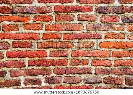 The texture of an old, destroyed wall and a building made of red, orange uneven bricks with cracks, gray cement and concrete. abstraction, background.