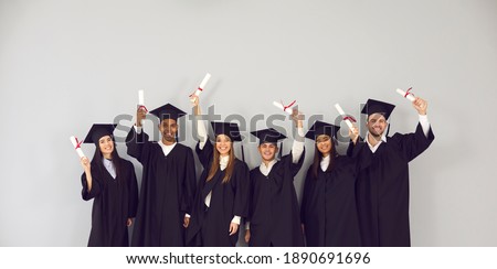 Study abroad website banner. Group of happy smiling diverse academy graduates holding up diplomas. International university students in traditional black academic gowns and caps celebrating graduation Royalty-Free Stock Photo #1890691696