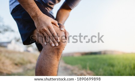 Sporty man in pain after sustaining a knee injury during a running training session. Royalty-Free Stock Photo #1890699898