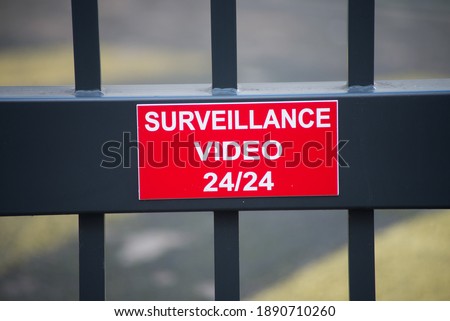 Closeup of red sign with text Surveillance video on a metallic fence in the street