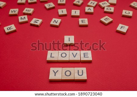 On a red background the inscription from wooden letters. I love you. Design for the holiday.