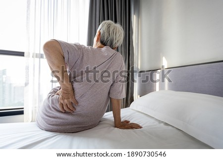 Stressed asian senior woman suffering from backache,sitting on bed massage her waist pain,unhappy old elderly people waking up in the morning after sleeping on uncomfortable mattress or bad posture Royalty-Free Stock Photo #1890730546