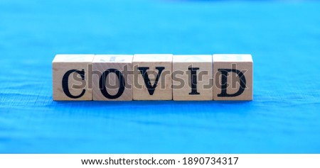 Covid virus word on wooden block on blue cloth with green light bokeh background as new normal because of COVID-19 virus., Corona virusl