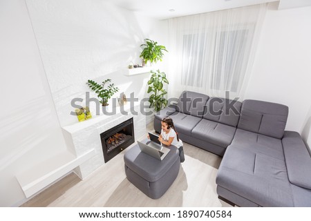 Photo of positive kid girl study remote sit desk table use laptop have online communication lesson with tutor writing report in house indoors