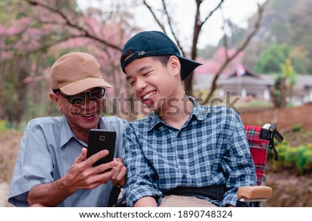 Disabled child on wheelchair and father in the city park, They have fun with selfie by smart phone, Life in the education age of special children,Happy disability kid travel in family holiday concept.