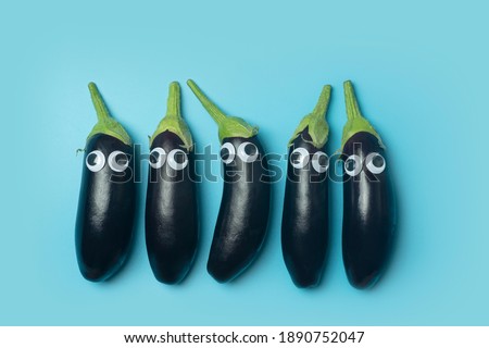 Kids food concept. Eggplant with eyes on a colored blue background. Funny vegetables and food for kids