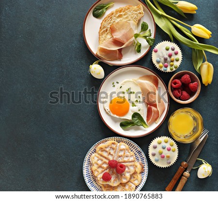 Breakfast food table. Festive brunch set, meal variety with fried egg, croissant sandwich, cheese platter and desserts. Overhead view