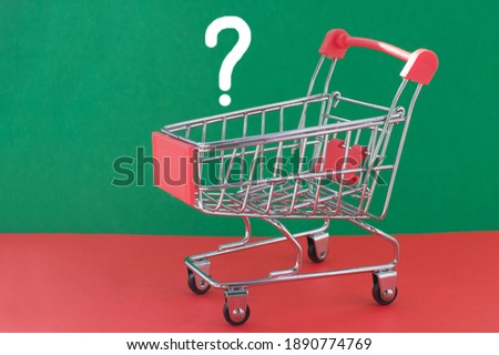 An empty shopping cart on a red and green background. The concept of reducing purchasing power and inflation. Close up.