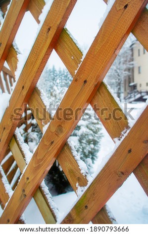 Wooden fence with a grid of boards in winter
