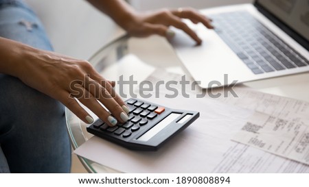 Crop wide banner view of woman sit at desk pay bills taxes on laptop online, manage home finances. Female busy calculating household expenses expenditures on calculator, make payment on computer. Royalty-Free Stock Photo #1890808894