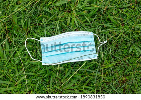 blue disposable protective mask, used for protection against cornavirus, thrown on green grass in Rio de Janeiro. Royalty-Free Stock Photo #1890831850