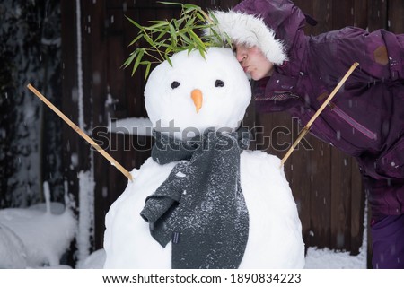 Woman in purple kissing snowman with green scarf