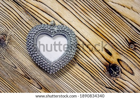 Heart photo frame background. A decorative silvery heart with a place for text on a wooden light table. Concept background for valentine's day, wedding, romantic invitation. Copy space