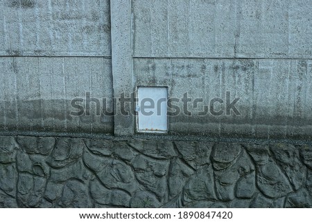 white metal box for electrical wires in a gray concrete wall of an outdoor fence