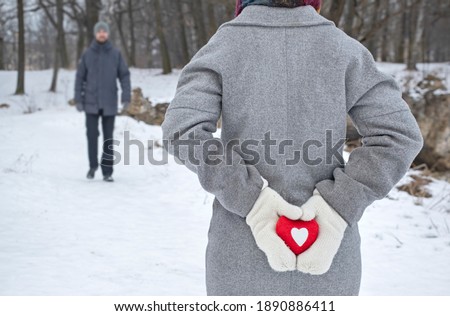 red heart in female hands, couple in love on a walk in a winter park, surprise for valentine's day, 14 february background
