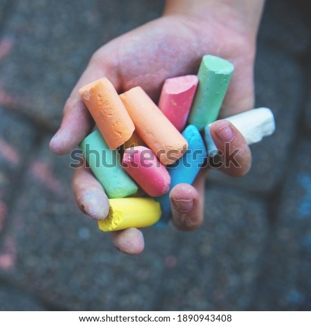 Blurred image Multi-colored colored chalk in a child's hand close-up. The concept of joy, positive, good mood and happiness. Blurred image, selective focus. No focus.