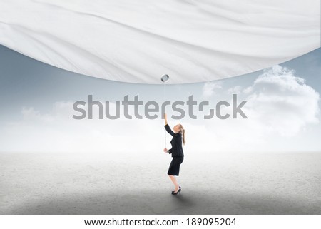 Businesswoman pulling a white screen against cloudy sky background