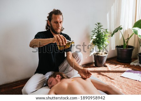Stock photo of relaxed man enjoying back massage while lying in the floor with oils.
