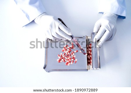 Focus on the picture of the doctor's hand, the colored pill on the dispensing tray by an antiviral drug pharmacist.
