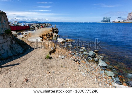 Undeveloped beach in the center of Vladivostok against the backdrop of residential townhouses and the blue sea