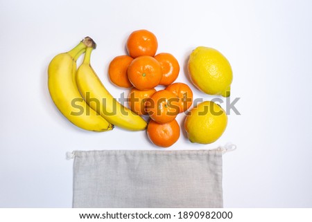 fresh fruits in recyclable eco bags on white background, top view