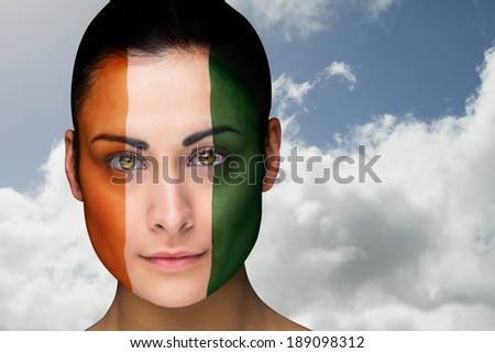 Composite image of beautiful brunette in ivory coast facepaint against bright blue sky with clouds