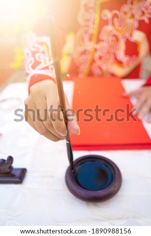 Close up Vietnamese scholar writes calligraphy at lunar new year. Calligraphy festival is a popular tradition during Tet holiday. Culture of Vietnamese Tet in springtime.