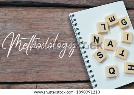 Selective focus of alphabet letters and notebook over wooden background written with Methodology.