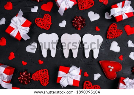 White teeth surrounded by gifts and hearts on a black background. Dental Valentine card. Valentine's day concept. 