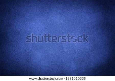 Navy blue matte background of suede fabric with vignette, closeup. Velvet texture of seamless indigo textile with gradient, macro. Structure of sapphire felt canvas backdrop.