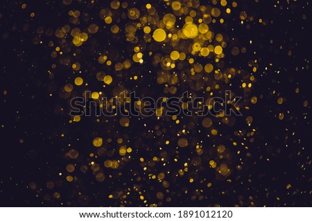 Gold bokeh of lights from water on black background