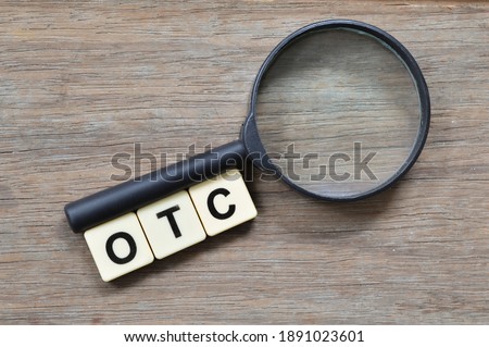 Top view of magnifying glass and alphabet letters with text OTC stands for Over-the-counter. Business concept.  Royalty-Free Stock Photo #1891023601